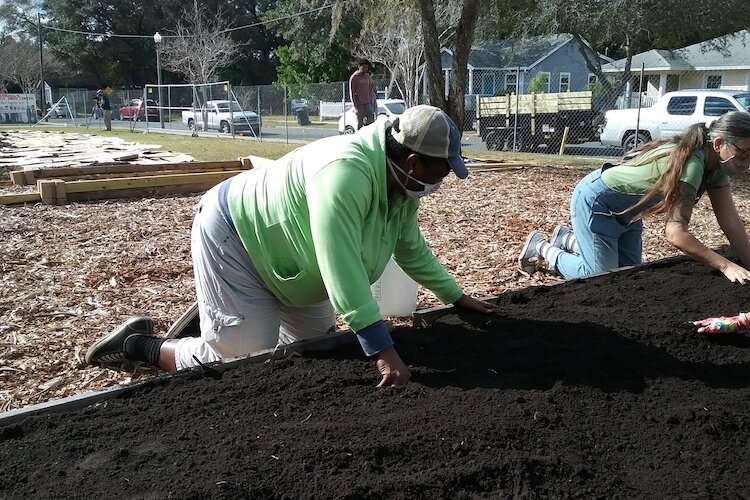 Community volunteer Stacey Rish spreads compost.