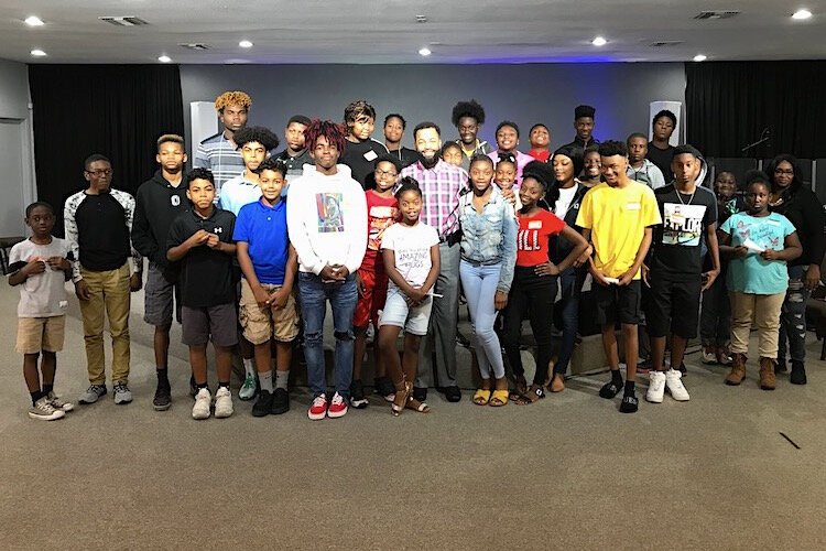 Leonard Burke surrounded by kids (pre-COVID-19) who see him as a role model.