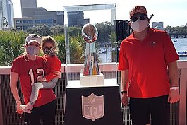 Michael Maurino, his wife, and his daughter pose with the Vince Lombardi Trophy at the Super Bowl Experience.