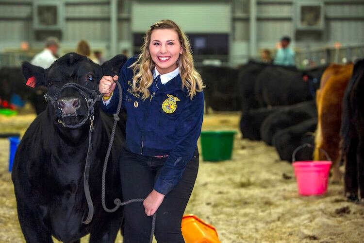 A young Future Farmer of America shows off her prize steer.