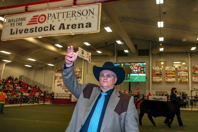 An auctioneer runs the show as young men and women who raise livestock see their animals go for bids.