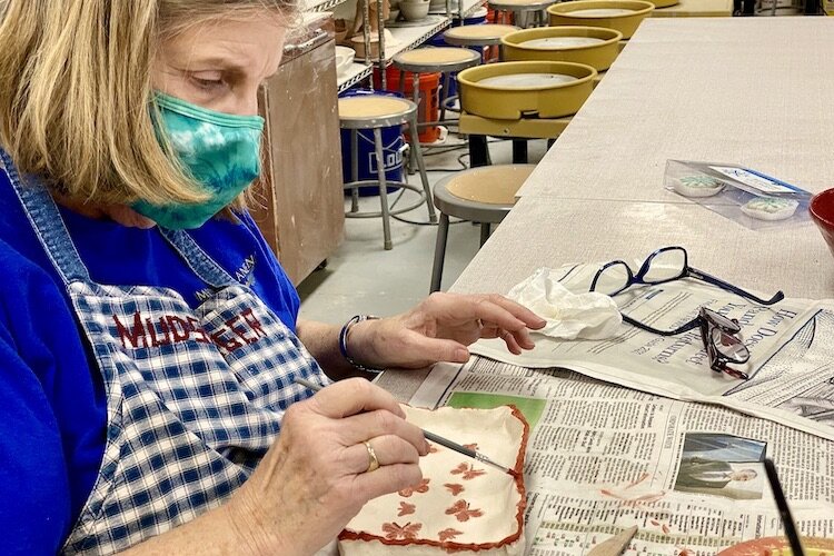 A participant in a ceramics class paints glaze on her most recent creation.