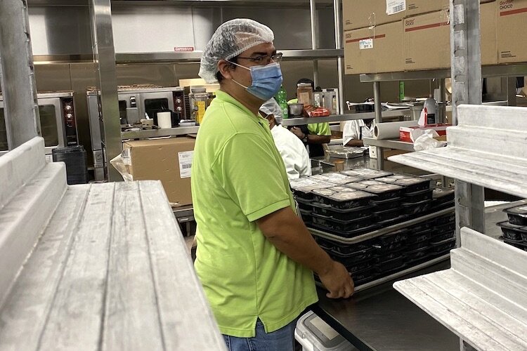 Kitchen staff, including Alan Linares, prepare trays of meals for shipment through the Homebound Meal Program or the Nonprofits Helping Nonprofits Program.