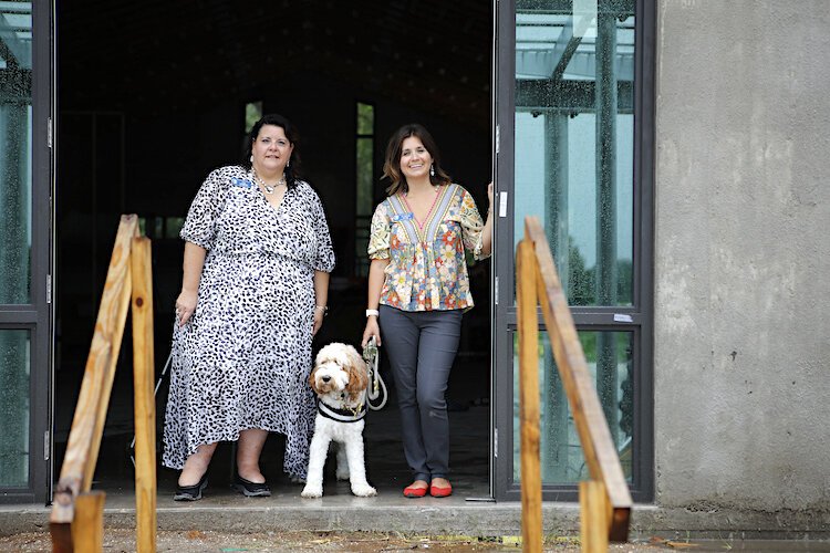 Resilient Retreat Executive Director Lisa Intagliata, therapy canine Journey, and Resilient Retreat Board Chair and Founder Dr. Sidney Turner stand in the doorway of the new Retreat Center.