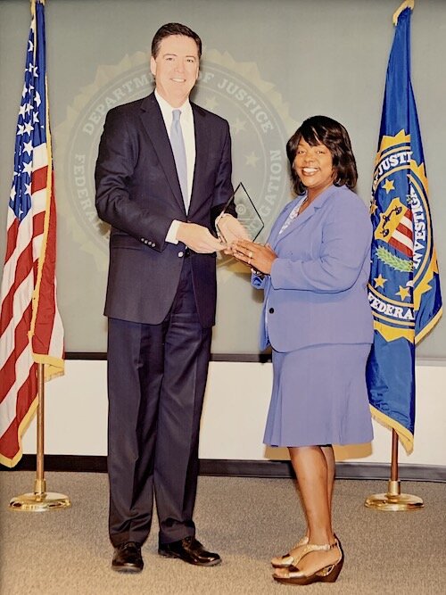 Hillsborough House of Hope Program Director Linda Chatters-Walker accepts a commendation from now former FBI Director James Comey.