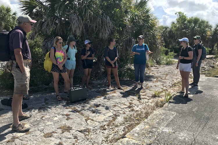 USF Sustainable Tourism Concentration Director, Dr. Brooke Hansen (in blue) discusses nuances of historical interpretation at the approximate site on Egmont Key where Seminoles were imprisoned by the U.S. Army in the late 1850s.