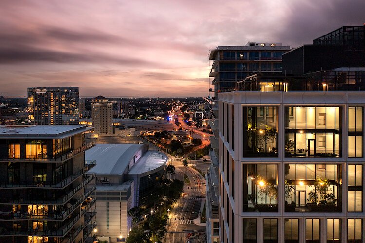 The floor to ceiling windows in Water Street Tampa's newest office building, Thousand and One, as seen at dusk in this drone image.