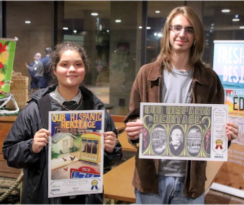 Students Kiara and Evan show winning entries in library poster contest.