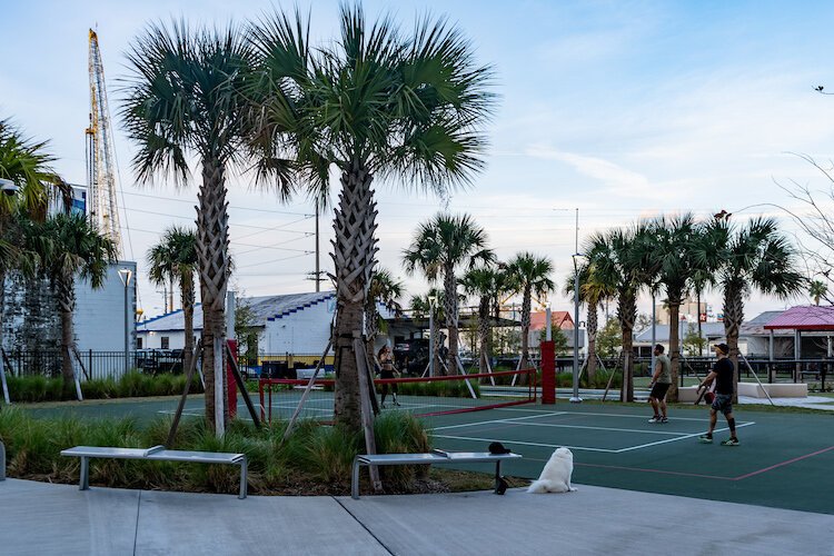 Friends engage in a doubles match among the planted trees and construction cranes at the Courtyard at Grand Central.