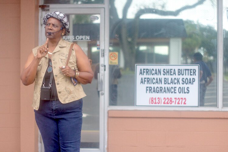 Tour guide Ersula Odom-McLemore gives some background on the history of the area while standing in front of African Extravanganza, a local Black-owned market for African fashion accessories, arts, crafts, books, and other novelty items.