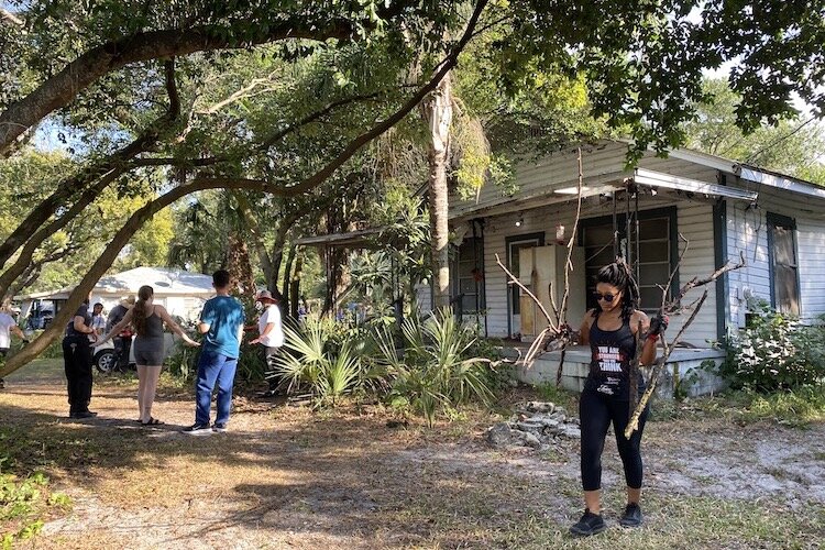Danielle Jones carries downed branches from Donna Cooper’s back yard. She and other volunteers work together to clean up neighborhood yards.