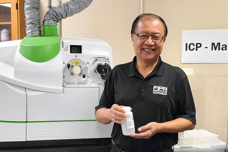 Dr. Patrick Zhang, research director of phosphate beneficiation and mining at Florida Polytechnic University’s Florida Industrial and Phosphate Research Institute (FIPR), shows a solution containing various rare earth elements in the institute’s lab.