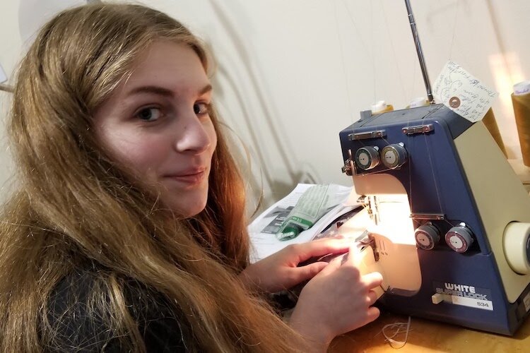 A young woman learns to use a serger machine.