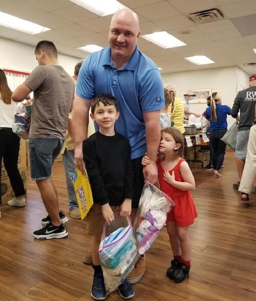 A dad and his two children bring items to be donated to Ukraine refugees.