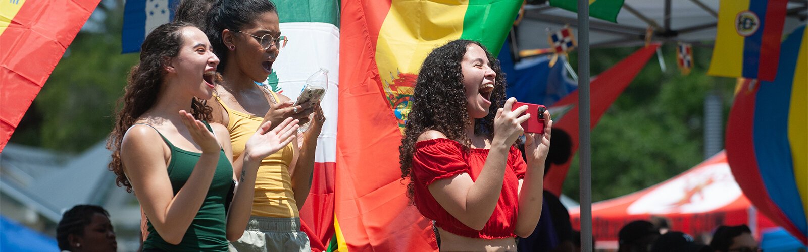Thalia Cortes, 19, Kathia Mackey, 26, and Britney Colon, 20, all from HCC, applaud the performers on stage during the Multicultural Family Day event at Water Works Park on Sunday.
