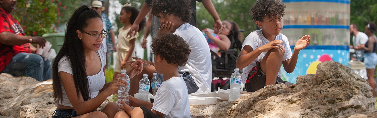 Vannesa Aguirre shares water and shade with her nephews Branden Smith, 6 (front), Hayden Smith, 11, and Landen Smith, 7, at the Multicultural Family Day event at Water Works Park on Sunday.