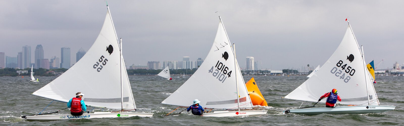 Sunfish sailors maneuver their crafts in sharp turns around buoys as part of the FWSA races.