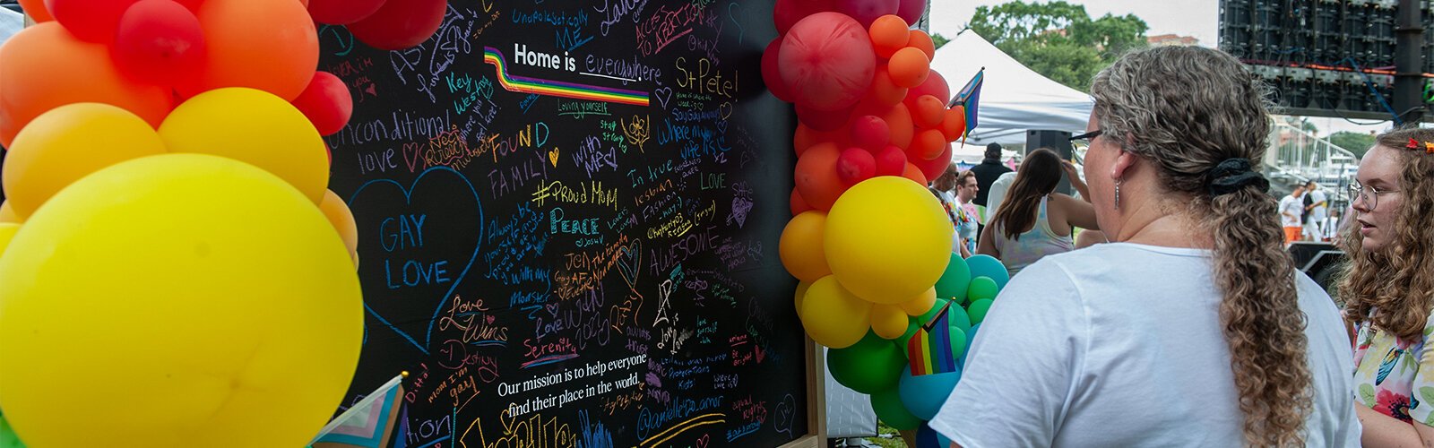 A large blackboard in the vendor area of the St. Pete Pride Parade is covered with messages of encouragement.