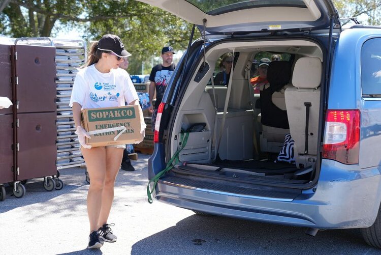 Pitching in on the Hurricane Ian recovery effort, a volunteer with Feeding Tampa Bay loads meals into a waiting vehicle.