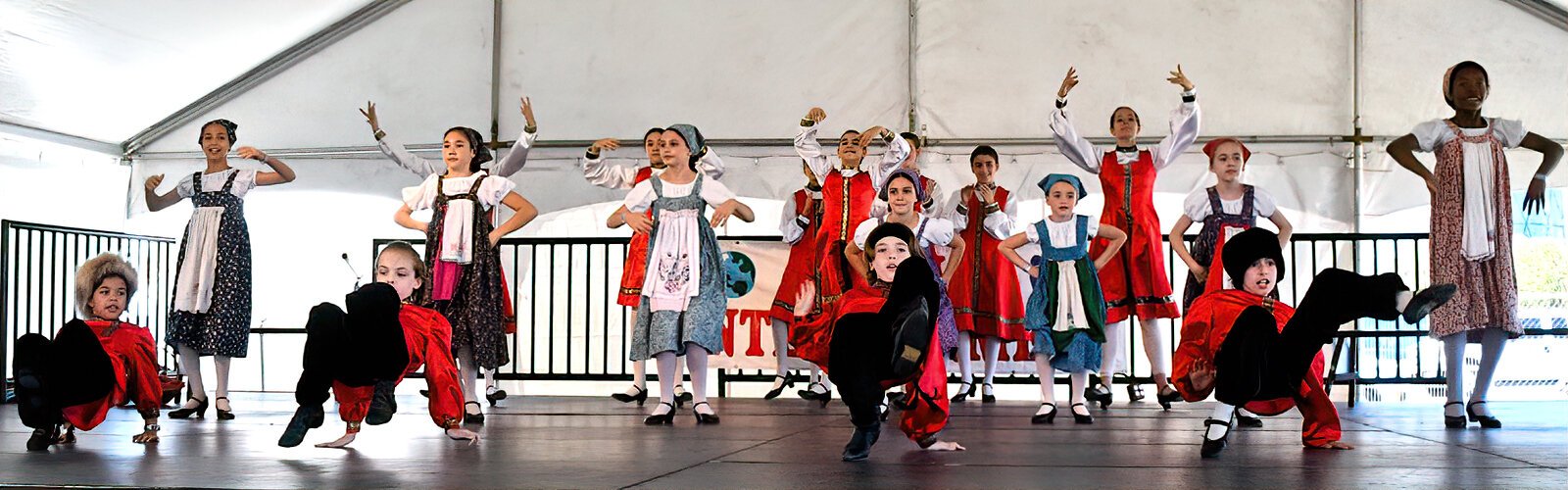 Young dancers from the St Pete Folk Ensemble perform a Russian dance on stage.