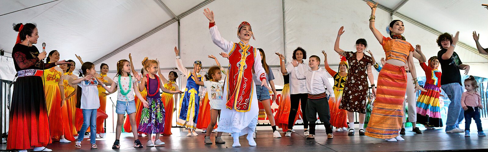 Upon invitation to join the Chinese dancers on stage, some children and adults from the audience learn a few Chinese dance moves.