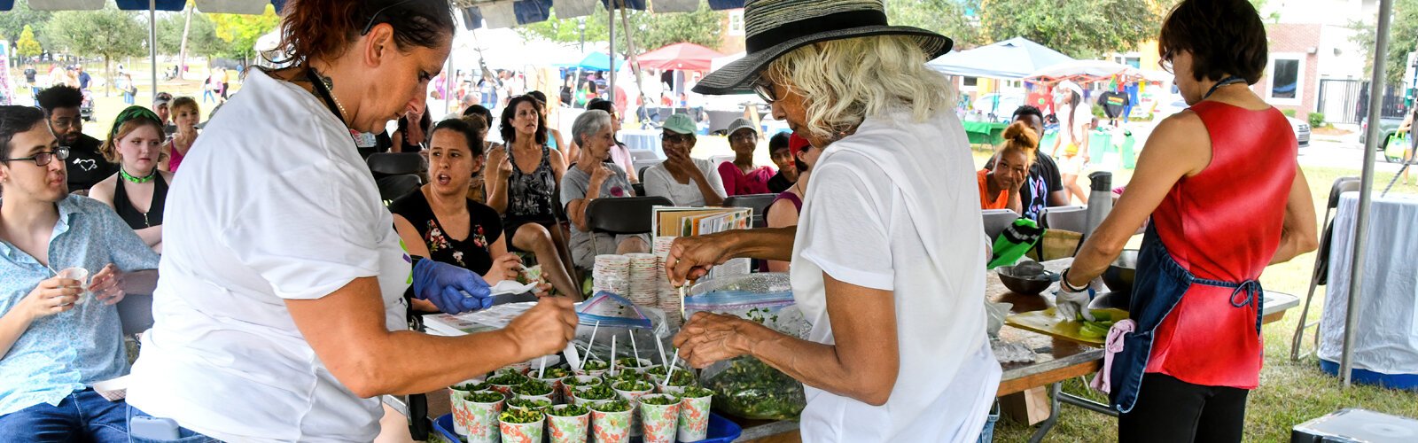 Two VegFest volunteers help with samples of Chef Timaree Hagenburger’s kale salad, prepared ahead of time, to give out to the audience to taste.