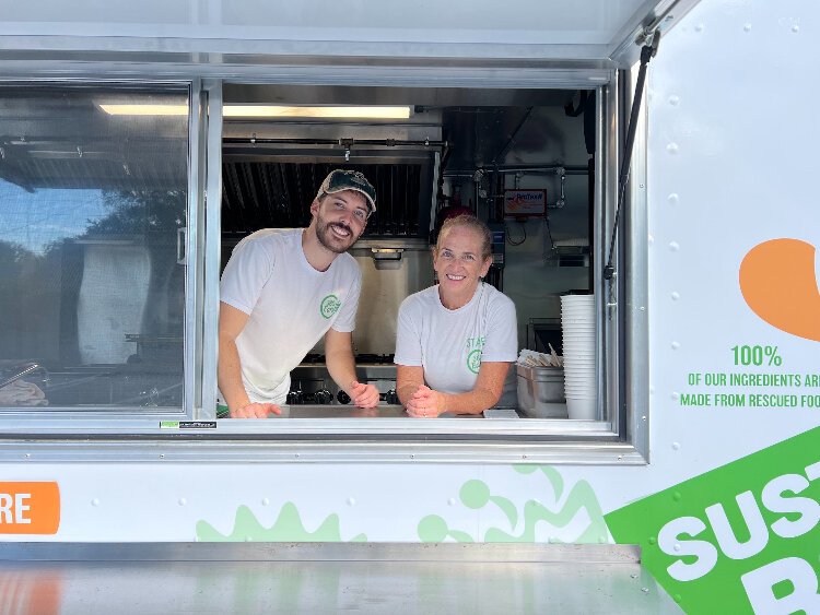 Cameron Macleish and Ellen Macleish of 360 Eats stand in the window of their charity's new food truck.