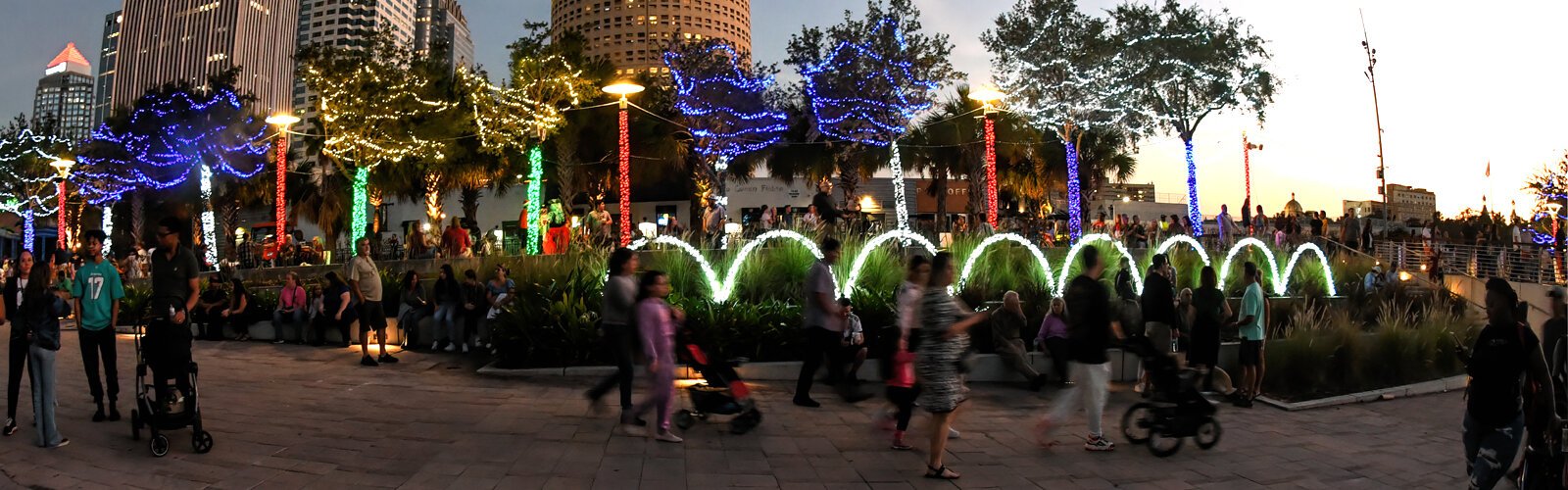 People stroll through Curtis Hixon Waterfront Park, enjoying the lights and holiday atmosphere.