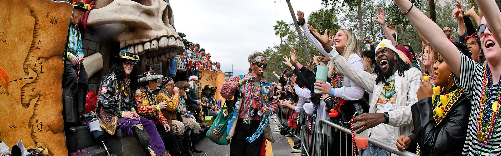 Excited revelers scream for beads as a pirate float passes by them.
