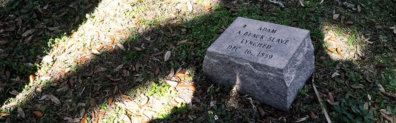 A simple stone marks the supposed burial site of Adam, a Black slave lynched by a mob in 1859 after he had been acquitted of the murder of a white man that he did not commit.