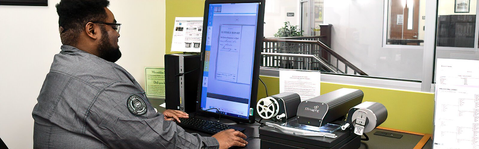 Librarian Shedriek Battle demonstrates how to use microfilm equipment. The Robert W. Saunders, Sr. Library offers free professional research assistance in African-American genealogy.