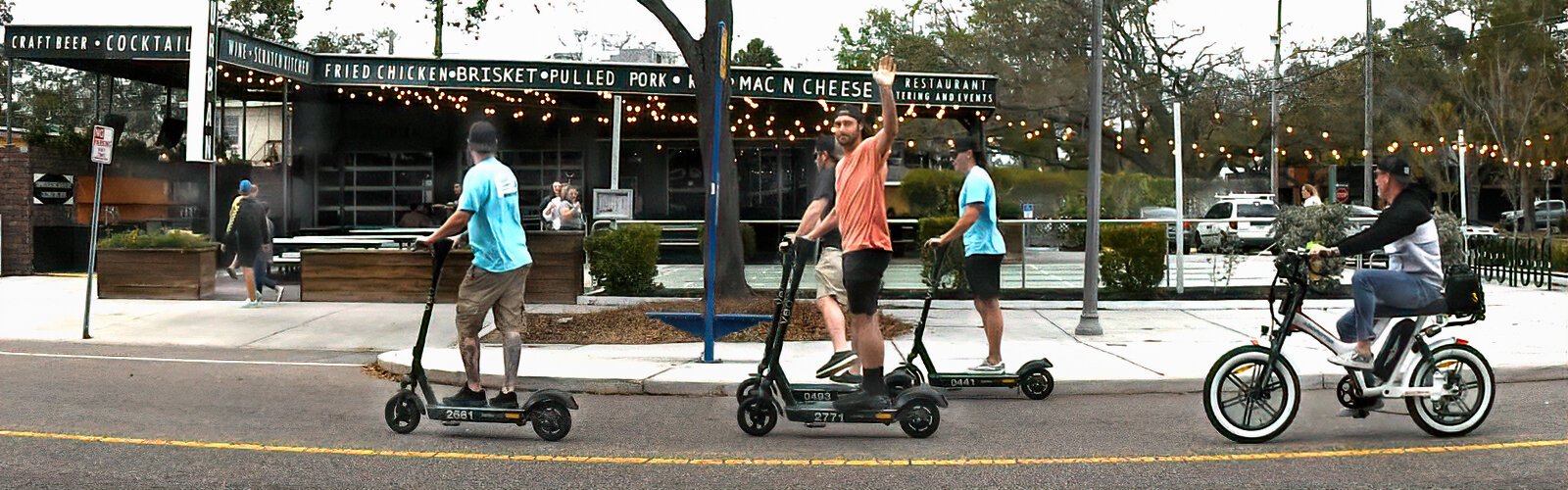 A group of friends on scooters rides down Central Avenue in the Grand Central District.