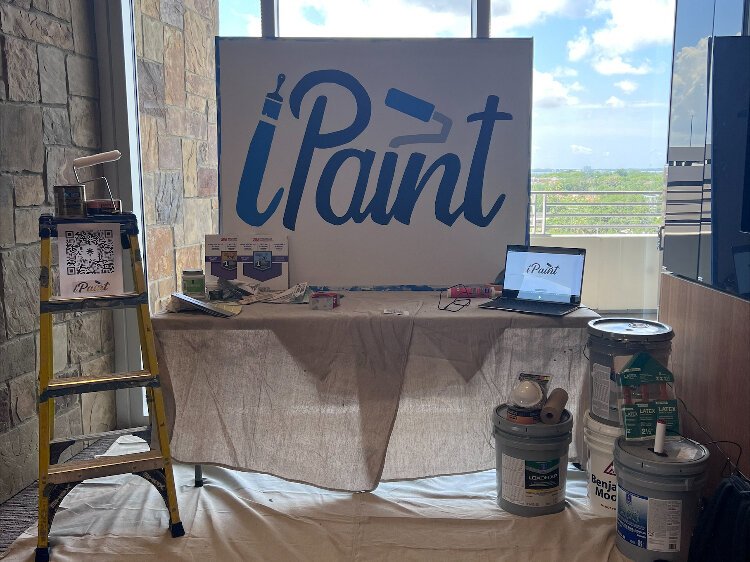 The iPaint booth at the UT Lowth Entrepreneurship Center New Venture Expo is decorated with the tools of the painting trade.
