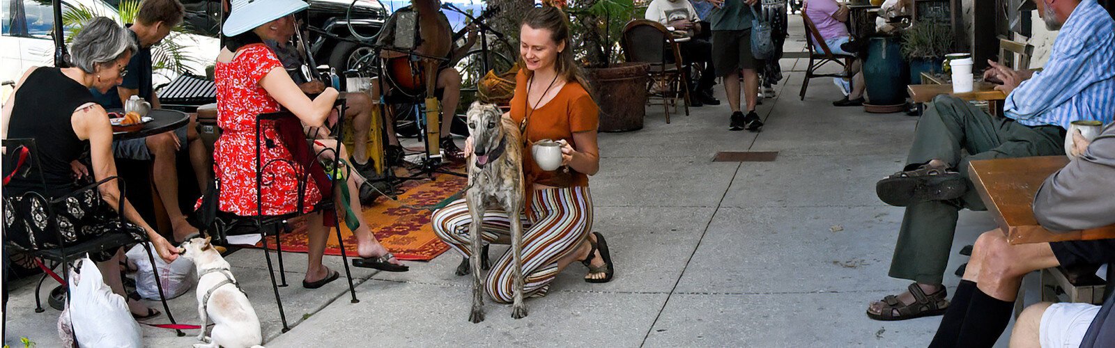 Kelli Harper, a barista at SumitrA Espresso Lounge +, takes a minute to pet sweet Shanti, a former greyhound racing dog adopted by customer Johanna Krynytzky. 