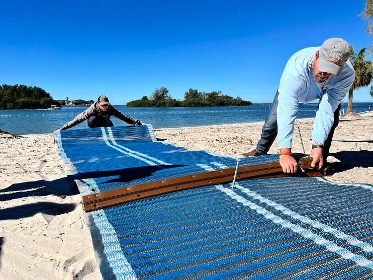 Workers roll out a Mobi-Mat at Anclote River Park in Holiday.