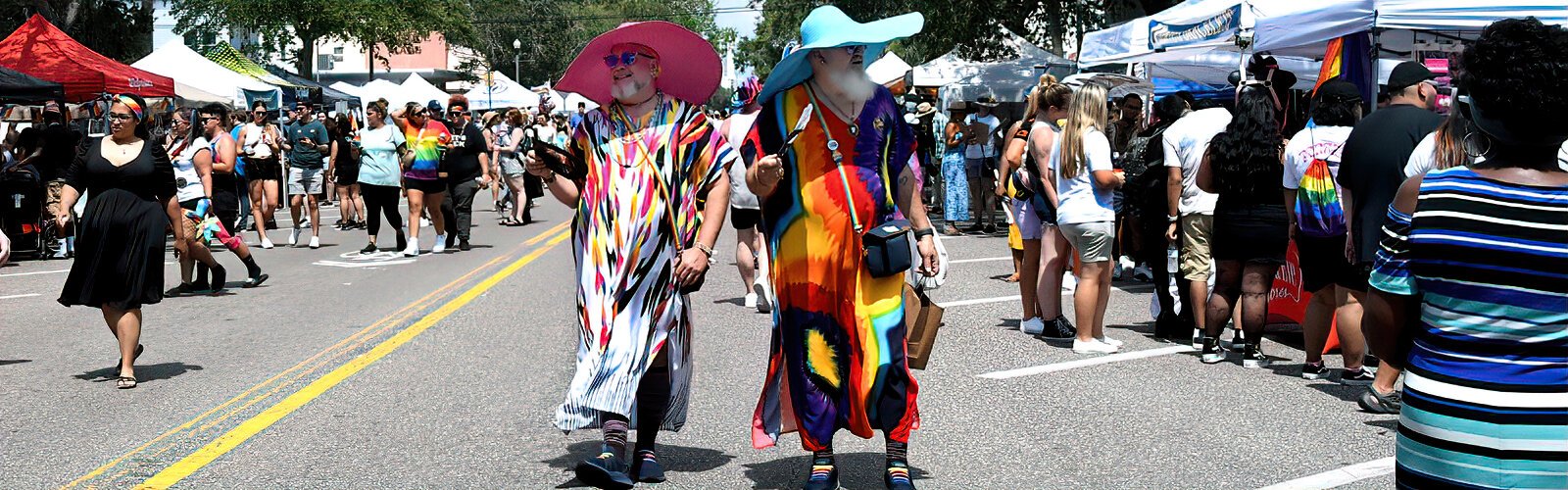 Shaded by their large hats, two festival-goers show off their pride as they wander down Central Avenue during the St. Pete Pride street festival, which had a carnival theme this year.