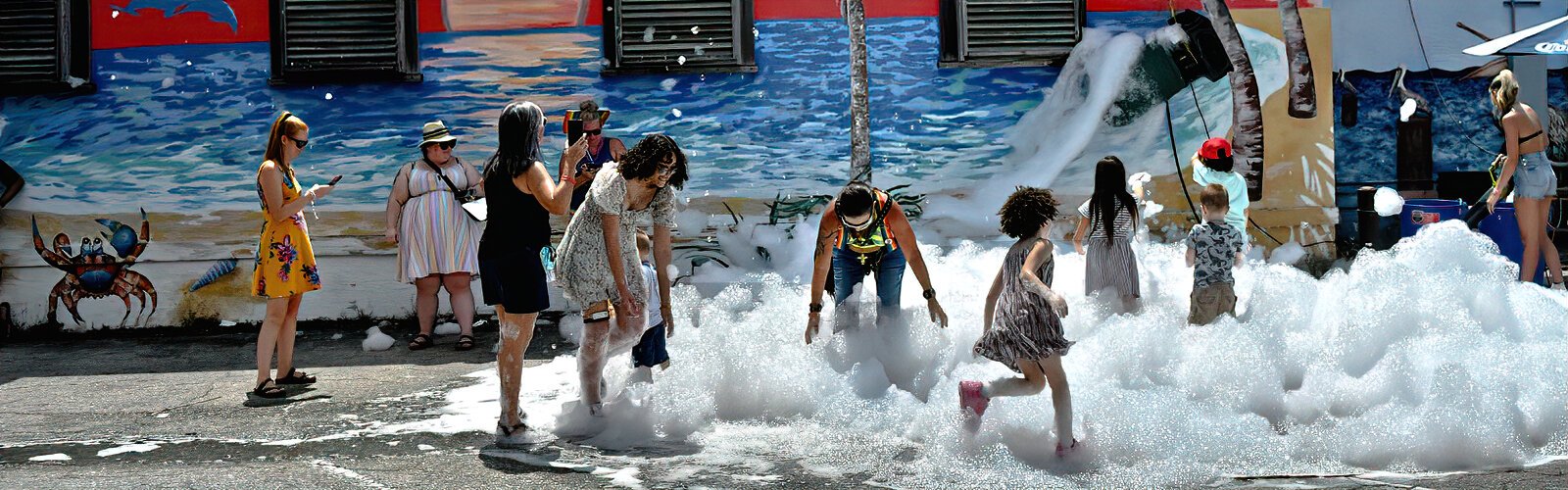 Festival-goers have fun in the foam dispensed by a foam-making machine during the St. Pete Pride Street Festival in late June.