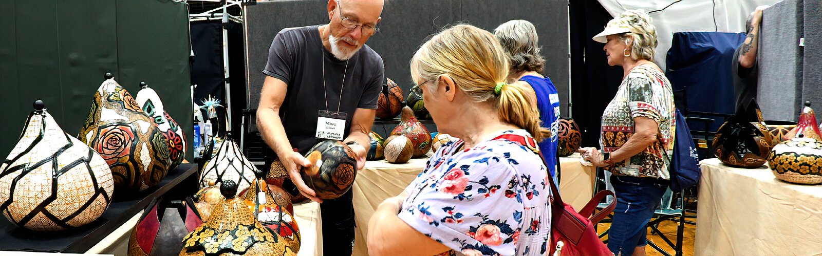 Wood artist Marc Gilmet discusses his beautifully carved and wood-burned gourds with a potential customer.