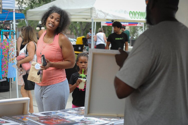 Trina Thompson and Kai Walton, 6, had some hard choices to make but finally decided on a painting from Allen Pettigrew of AP Art Studio at the Ybor City Saturday Market.