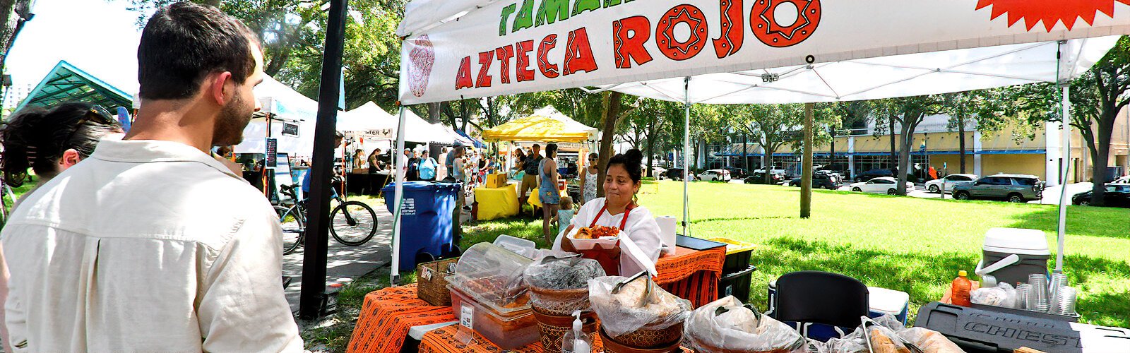 A couple gets an order of authentic Mexican food with a smile from Roci Mendez, the owner and chef of Azteca Rojo, which specializes in handmade tamales.