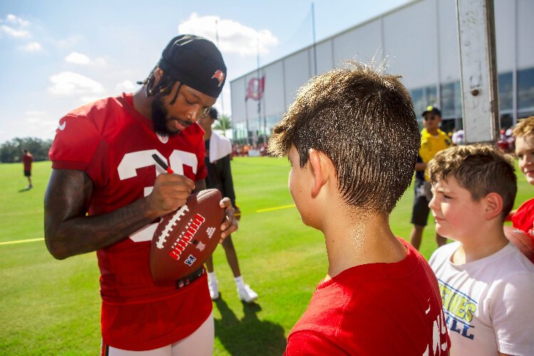 Tampa Bay Buccaneers cornerback Don Gardner autographs a football for a young fan during the team's annual Community Impact Day event at training camp. 