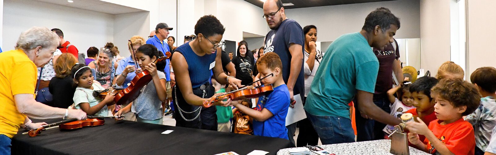 The Florida Orchestra’s Manager of Education and Community Janae Earl shows a child how to handle a violin at The Florida Orchestra’s well attended “Petting Zoo."