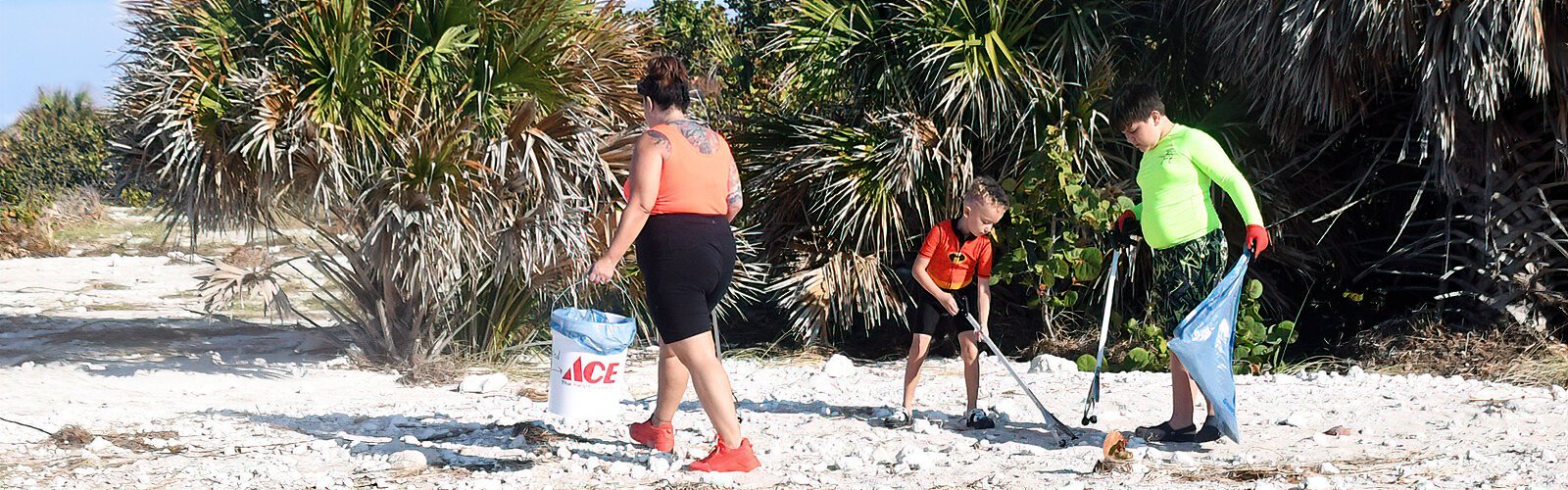 Holding a bucket donated by  ACE Hardware, Nathalie participates in the family-friendly cleanup event with her two children Nixon, 6, and Exavier, 11, to develop in them awareness of beach pollution.