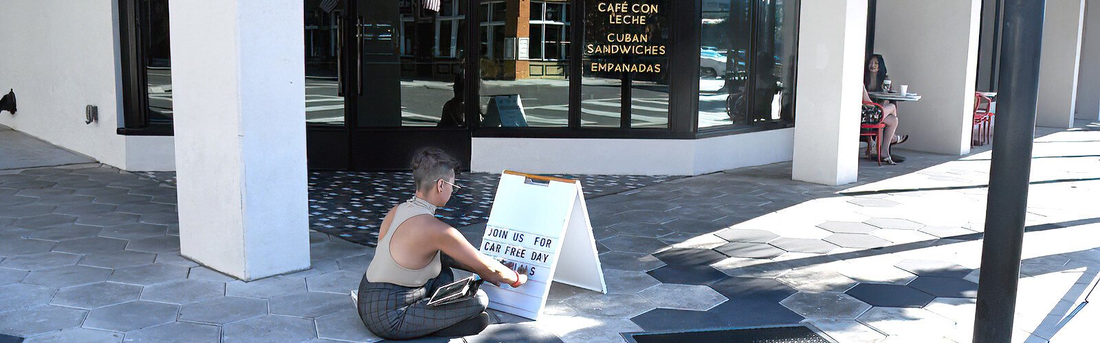 Alexis Gittens, manager of Café Quiquiriqui in Ybor City, sets up an A-frame sign in front of the establishment to announce specials and 10% discount in honor of World Car-Free Day on September 23rd.