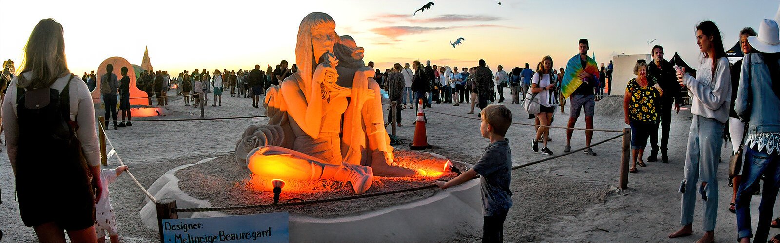 A youngster takes time to admire Mélineige Beauregard’s exquisite sculpture, “Take Time to Smell the Roses," as flood lights illuminate it at sunset.