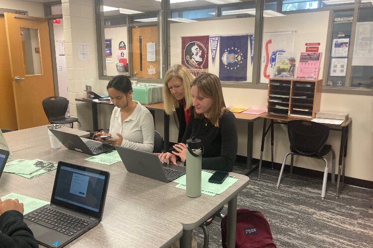 Carole Lessley, the college and career coordinator at Dunedin High, School, answers a question from senior Campbell Hudson as senior Kim Abrams works next to them.