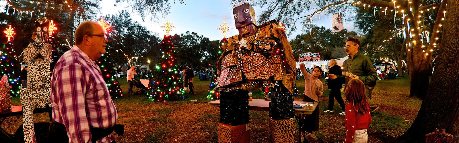 As a visitor looks on, artist Ben Gilton speaks with children about his giant sculptures created from cardboard boxes mixed with other recycling materials.