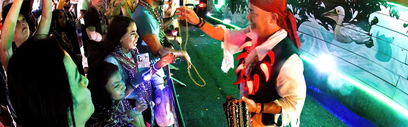  A Castaways Krewe member hands out beads to a young girl, happy to add to her growing bounty.