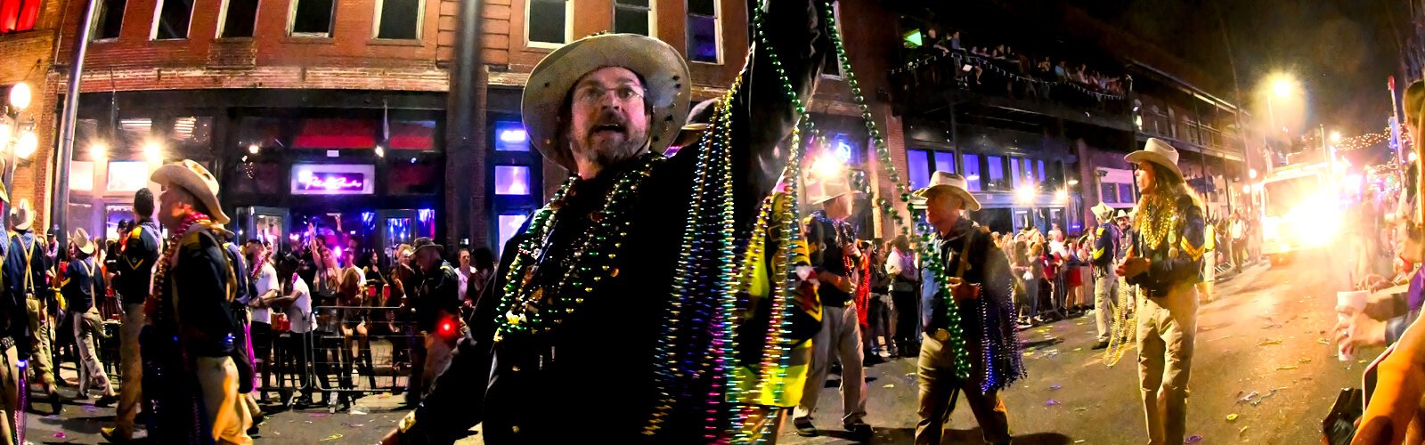 A member of the Rough Riders Krewe tosses beads to the crowd packed along Seventh Avenue in Ybor City for the Knight Parade.