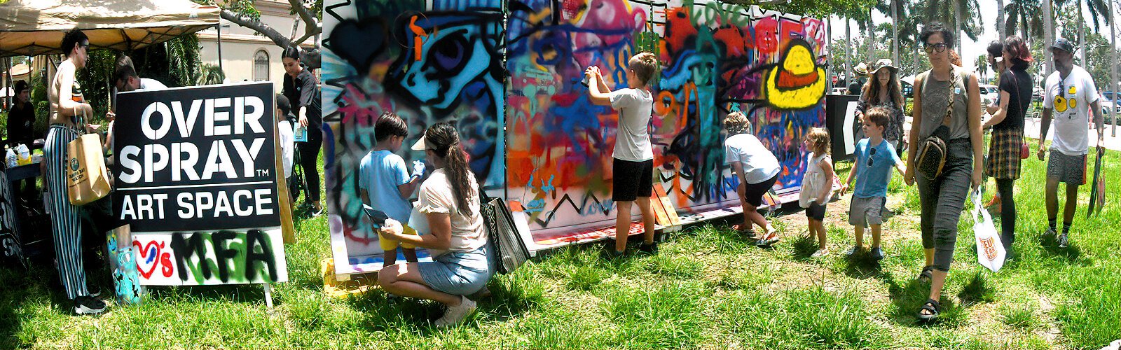At MFA St Pete’s Painting in the Park 2025, budding artists experiment with spray-painting on a huge panel provided by Gulfport’s Overspray Art Space.
